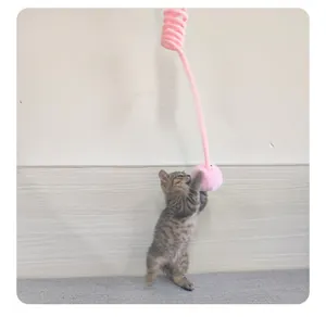 Kätzchen spielt mit einem rosa Plüsch-Feder-Pompon-Katzenspielzeug