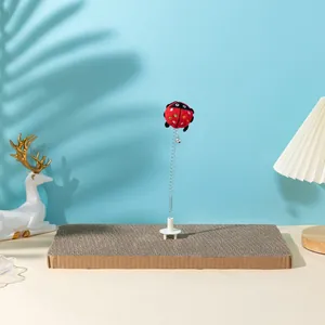 Detailed view of cat scratching board with a spring-mounted plush ladybug toy attachment.