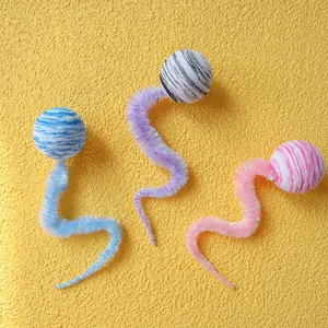 Dettaglio di giocattoli di peluche colorati per gatti con code a bruco su fondo giallo
