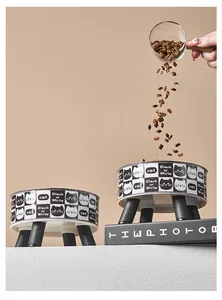 Primer plano de comida cayendo en un cuenco elevado para gatos con diseño de damero.