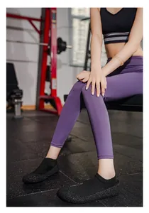 Dettaglio di scarpe da yoga a calzino nere traspiranti con suole antiscivolo testurizzate.