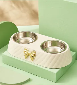 Detail of cream diamond-textured pet feeder with gold bow and stainless steel bowls