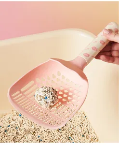 Close-up van een roze macaron kattenbakschep met hartvormige gaten voor het schoonmaken