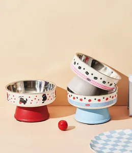 Elevated stainless steel pet bowls with cute cat and fruit patterns in a warm setting