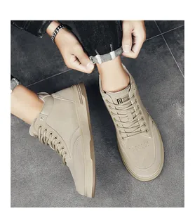Sneakers casual alte da uomo color beige indossate su un pavimento in piastrelle grigie