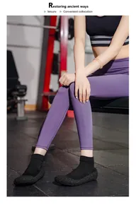 Detailansicht leichter schwarzer Yoga-Sockenschuhe, die ein Model im Fitnessstudio trägt.