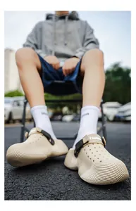 Detailed view of designer beige clog shoes with wavy texture and adjustable strap