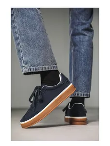 Detail lifestyle shot of navy blue suede men's casual sneakers with brown gum soles