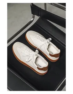 Detailed top view of men's white leather sneakers with brown suede accents on a black chair