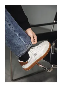 Close-up of stylish white suede sneakers with gum soles on a model wearing denim jeans