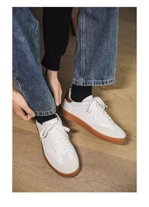 Close-up view of premium white leather sneakers featuring suede toe and brown gum sole