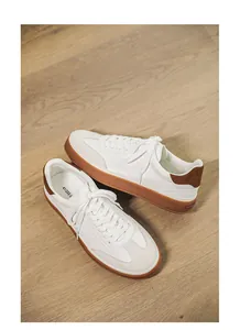 Close-up of white suede leather sneakers for men featuring stylish brown platform soles