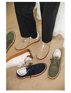 Close-up of premium suede casual sneakers in multiple colors on a natural wooden floor