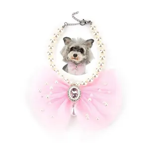 Close-up of elegant pet pearl necklace with large pink lace bow and crystal pendant.