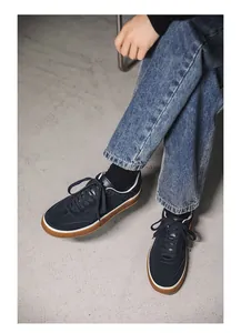 On-feet view of navy blue suede sneakers with white trim and stylish gum soles