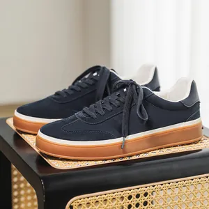 Stylish navy blue suede men's sneakers with gum soles displayed on a modern rattan stool
