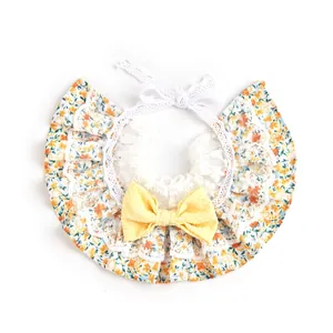 Detalle de babero para mascotas con encaje floral y lazo amarillo sobre fondo blanco.