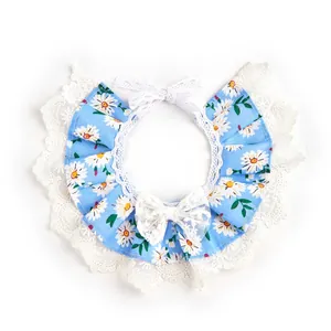 Detalle del babero para mascotas con flores azules, encaje blanco elegante y lazo.