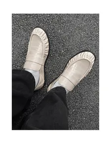 Top view of beige crocodile embossed loafers with pleated edge details on asphalt