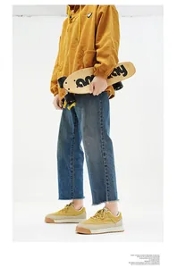 Vue latérale de baskets vintage jaunes à semelle épaisse portées avec un jean et un skateboard.
