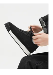 Gros plan de baskets rétro noires à plateforme avec tissu respirant et semelle blanche