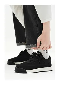 Vue détaillée de baskets noires respirantes portées avec un jean en denim noir usé.