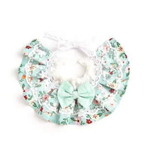 Primer plano de un babero floral para mascotas con encaje blanco y lazo verde