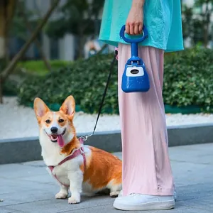 Draagbare blauwe hondenpoepschep vastgehouden door een persoon buiten met een Corgi-hond