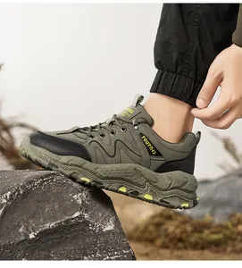 Side view profile of green and black men's outdoor hiking shoes stepping on a rock