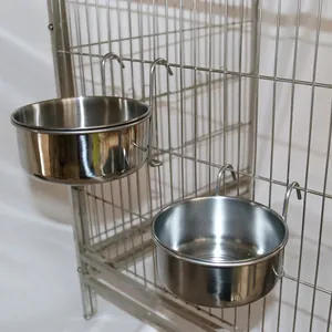 Close-up detail showing stainless steel feeding bowls securely hooked onto a metal bird cage