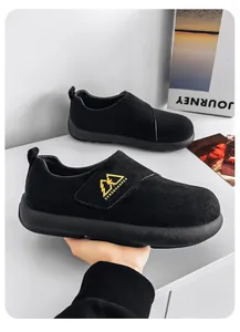 Vista detallada de un mocasín de ante negro para hombre con logotipo amarillo.