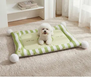 Close-up of a green striped pet cooling mat with plush pom-poms and a dog on top