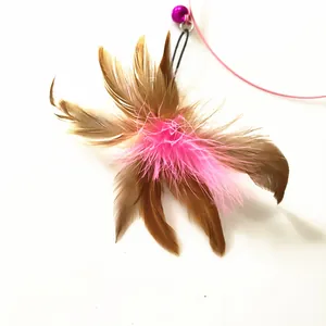 Macro view of a cat toy feather teaser featuring pink accents and a small bell