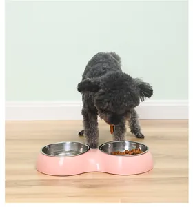 Pink pet double bowl with stainless steel inserts shown with a poodle eating