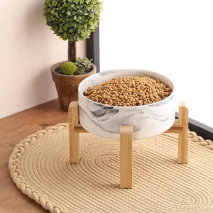 Vue détaillée d'un bol pour animaux en céramique marbrée sur un support en bambou naturel.