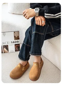 Detalle de mocasines de gamuza marrón para hombre con bordado de montaña.