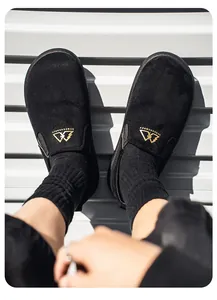 Primer plano de zuecos de gamuza negra para hombre con detalles de logo dorado