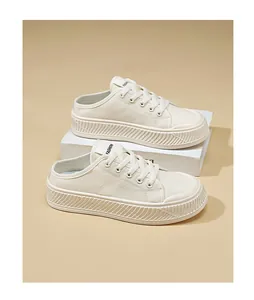 Detail of cream canvas mule sneakers with thick platform sole and lace-up design.