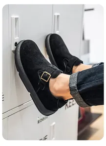 Detalle de mocasines de ante negro para hombre con hebilla dorada en un casillero