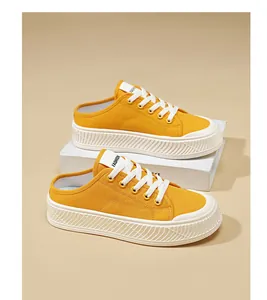 Yellow canvas mule sneakers with thick white platform soles in a studio setting