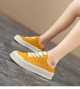 Side view of yellow canvas mule sneakers with white laces and thick platform sole