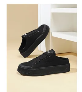 Close-up view of black canvas mule sneakers with thick ribbed soles and lace-up front