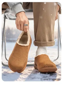 Close-up of men's winter suede clogs with plush lining in a snowy outdoor setting