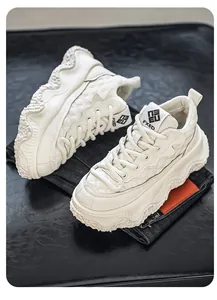 Close-up of off-white chunky platform sneakers with thick textured soles and denim backdrop