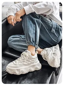 Close-up of chunky white platform sneakers with textured leather and wavy sole