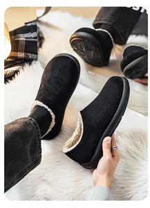 Detail view of high-quality men's black fleece-lined slip-on shoes on a white faux fur rug