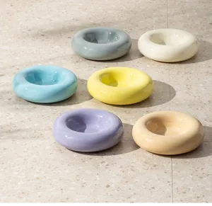 Sechs bunte, donutförmige Keramik-Napfschalen auf einem stilvollen Terrazzoboden.