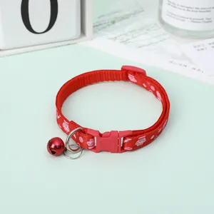 Detailed close-up view of a red pet collar with pink paw prints and a matching bell