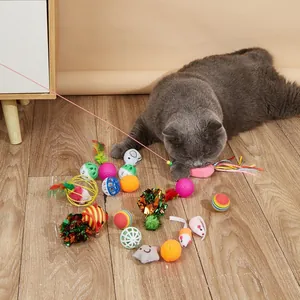 Dettaglio di un gatto grigio che gioca con un set di palline e topi giocattolo colorati