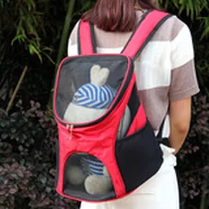 Detailed view of red and black pet carrier backpack worn by person in outdoor setting